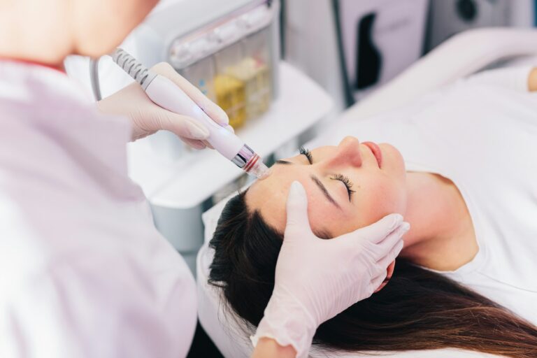 Cosmetologist doing hydrafacial treatment on woman face Image description