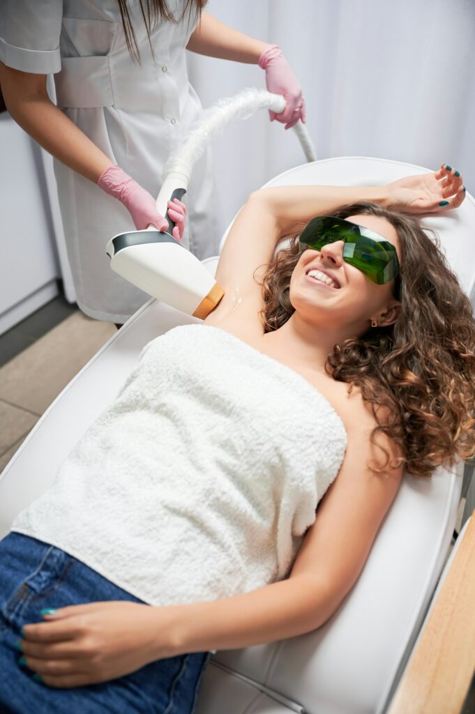 Joyful woman receiving underarm laser hair removal treatment.